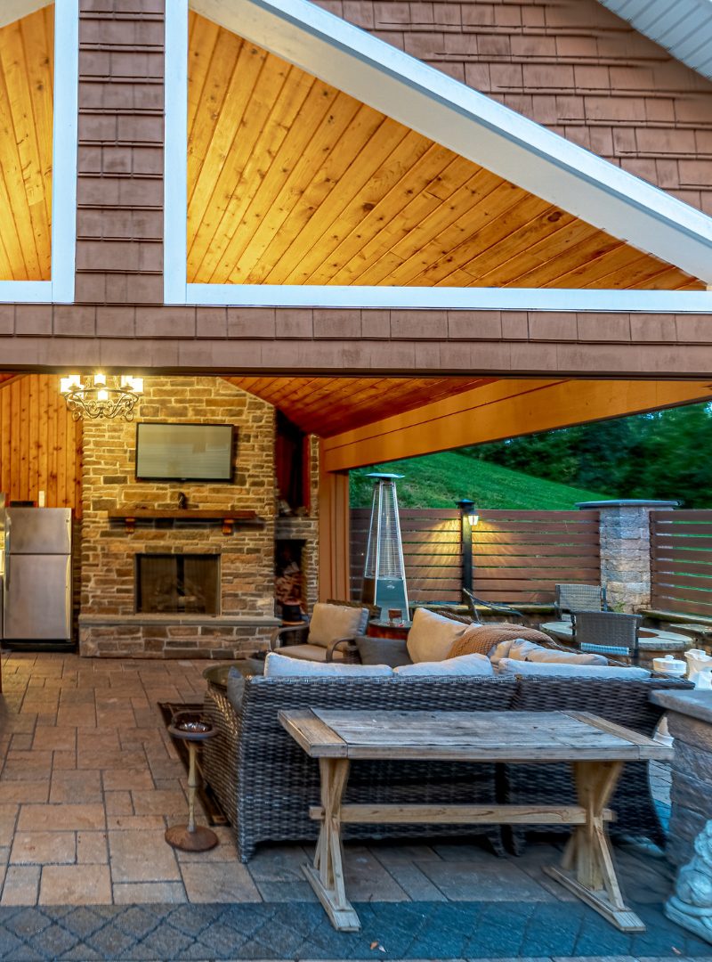 Covered outdoor living area with stone fireplace, paver patio, and seating built during a fall hardscaping project in Berlin, Connecticut.